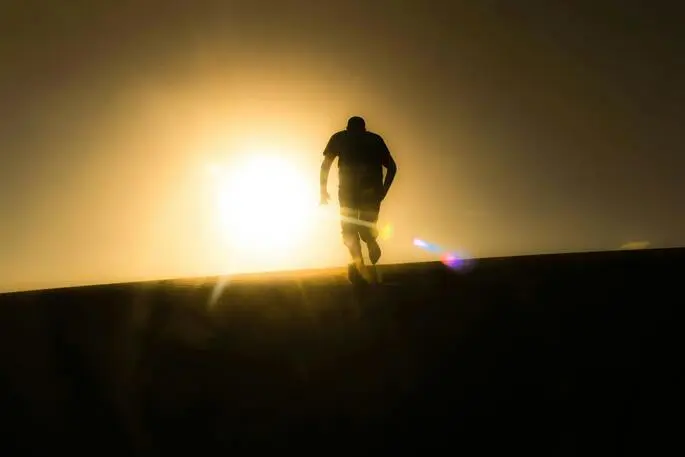 a man running on uphill towards the sun