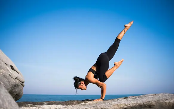 woman practicing yoga on the beach and the sky is blue 